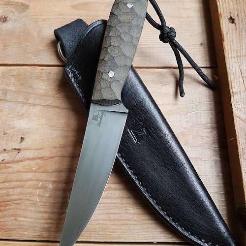 Slim and sharp utility knife in O1 carbon and linen micarta with black leather sheath.